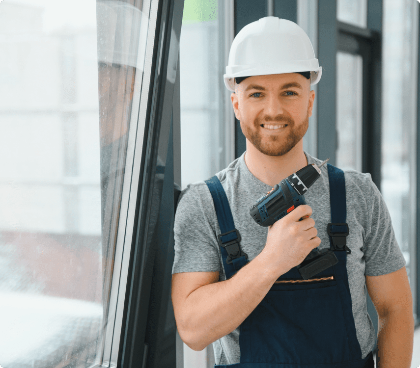 A Person Wearing a Hard Hat and Overalls Holding a Drill